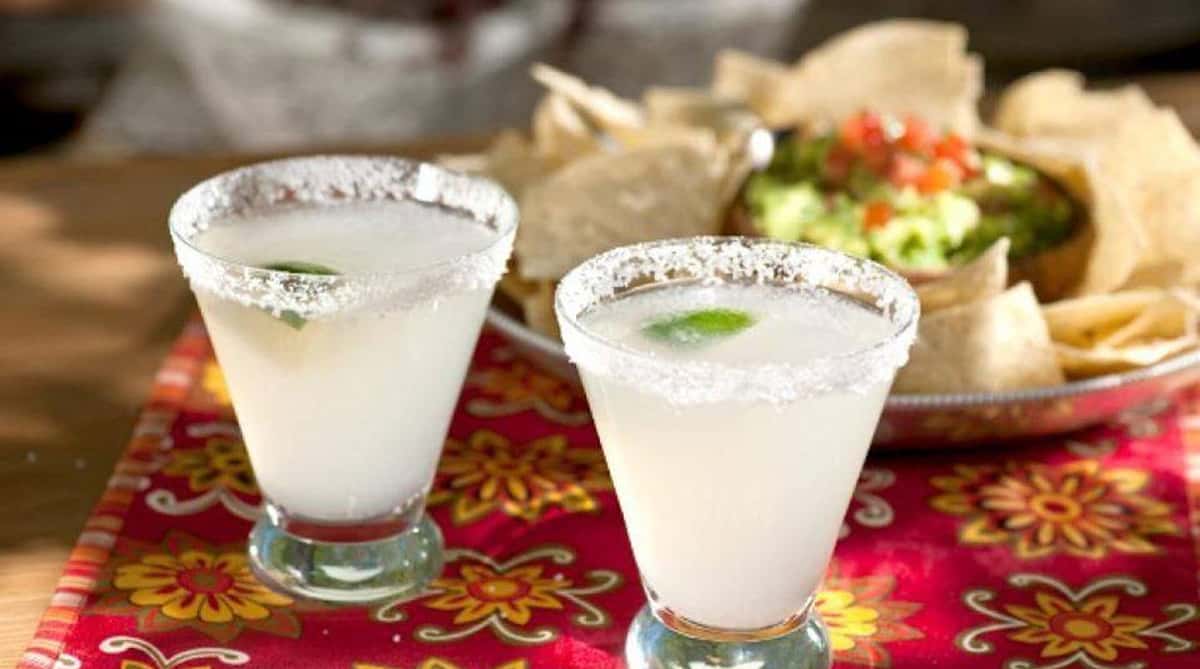 Two lime margaritas with salted rims on a colorful table setting.