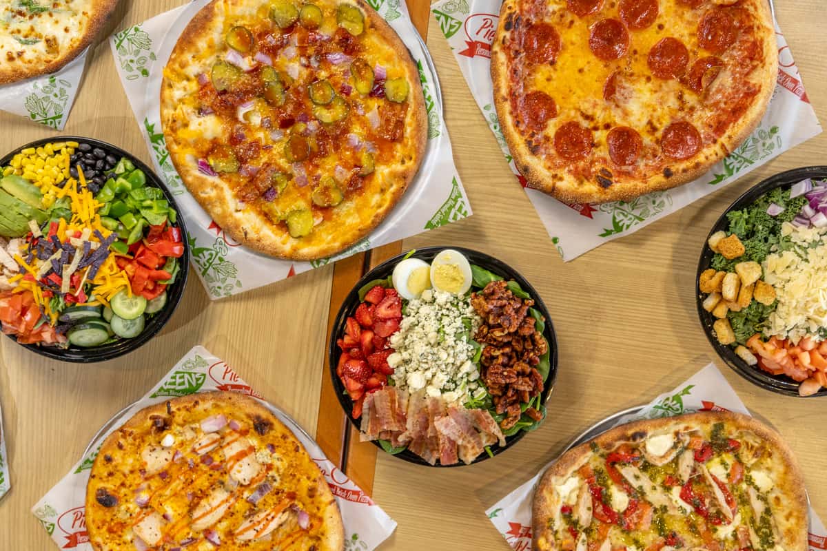 spread of pizzas and salads of different varieties