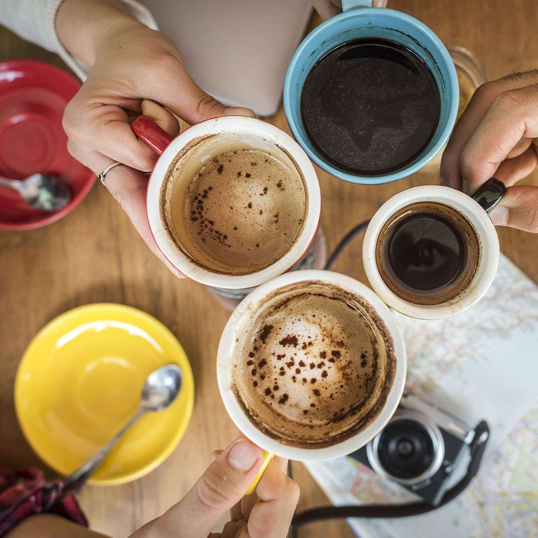 An image of several people toasting their cups of coffee