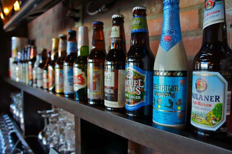 assortment of beer bottles lined up on the bar
