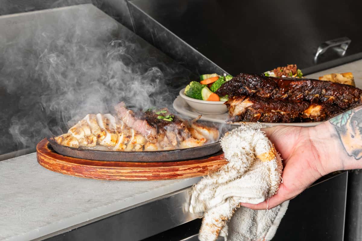 Sizzling grilled chicken and barbecue ribs served hot with fresh vegetables in a restaurant kitchen