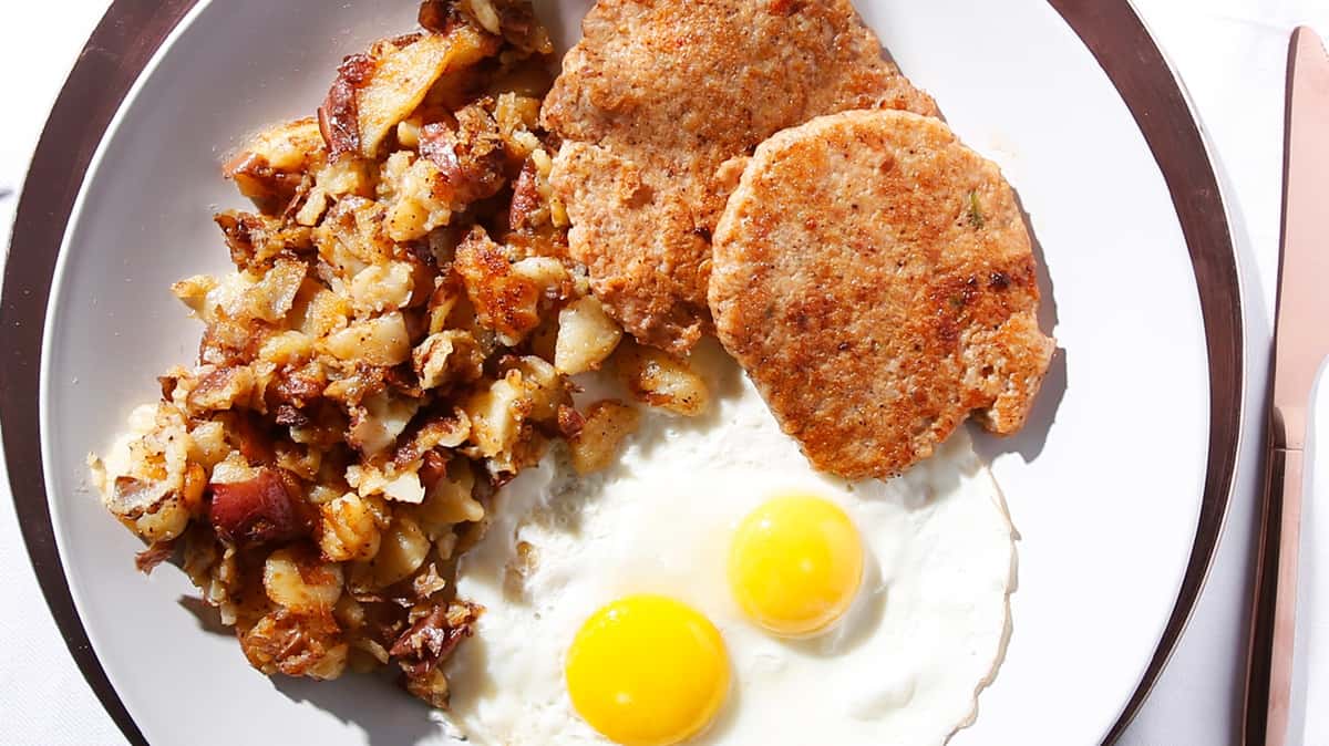 Country-style breakfast with eggs, sausage, potatoes, and gravy.
