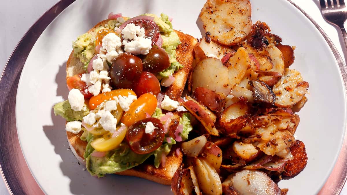 Breakfast plate with salad, feta cheese, tomatoes, and roasted potatoes.
