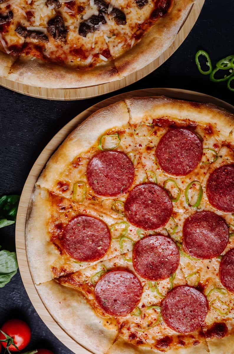 A close-up view of a pizza topped with circular slices of pepperoni and green bell peppers on a golden crust.