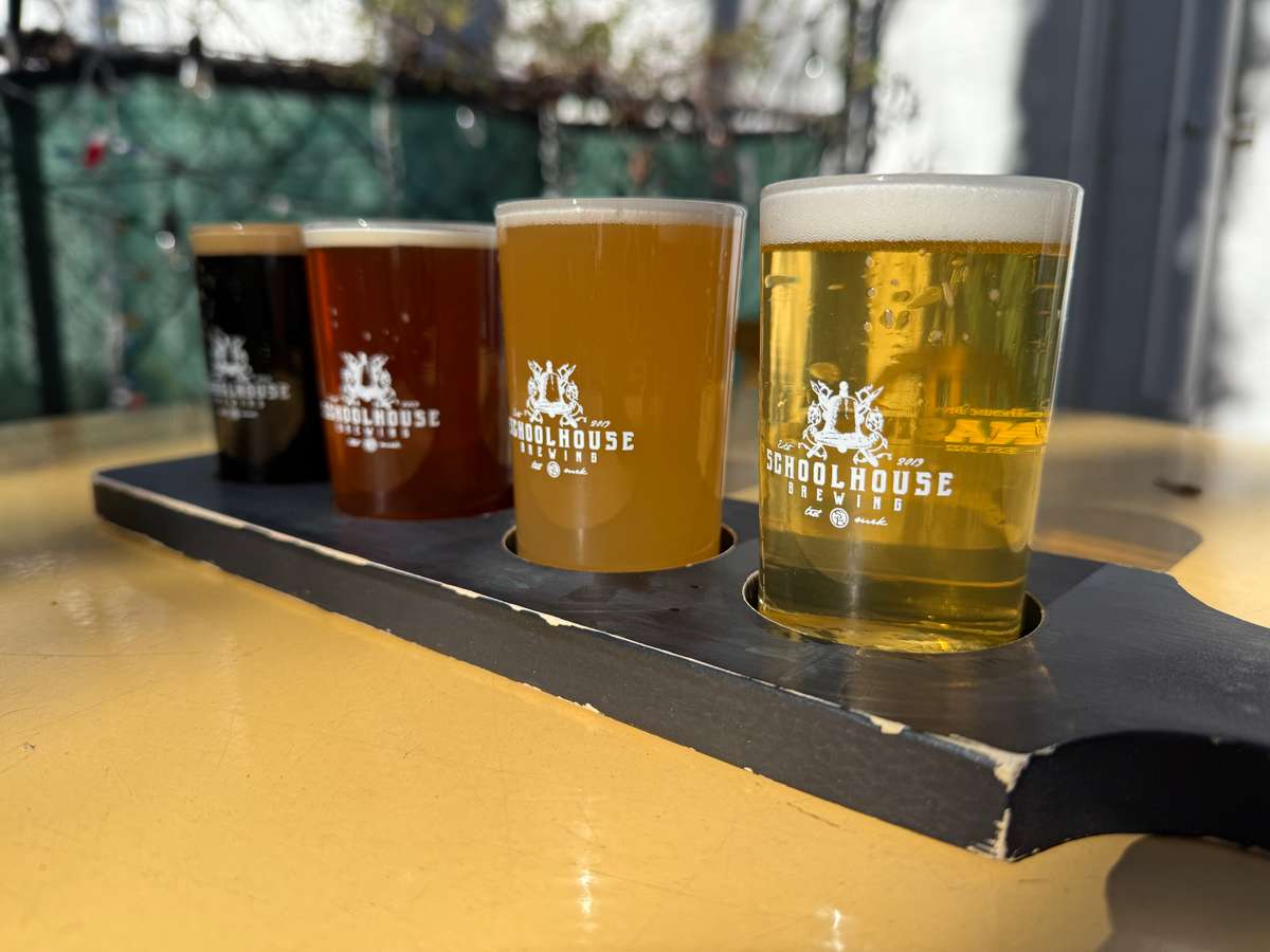 Flight of four Schoolhouse Brewing beers on a branded tasting paddle.