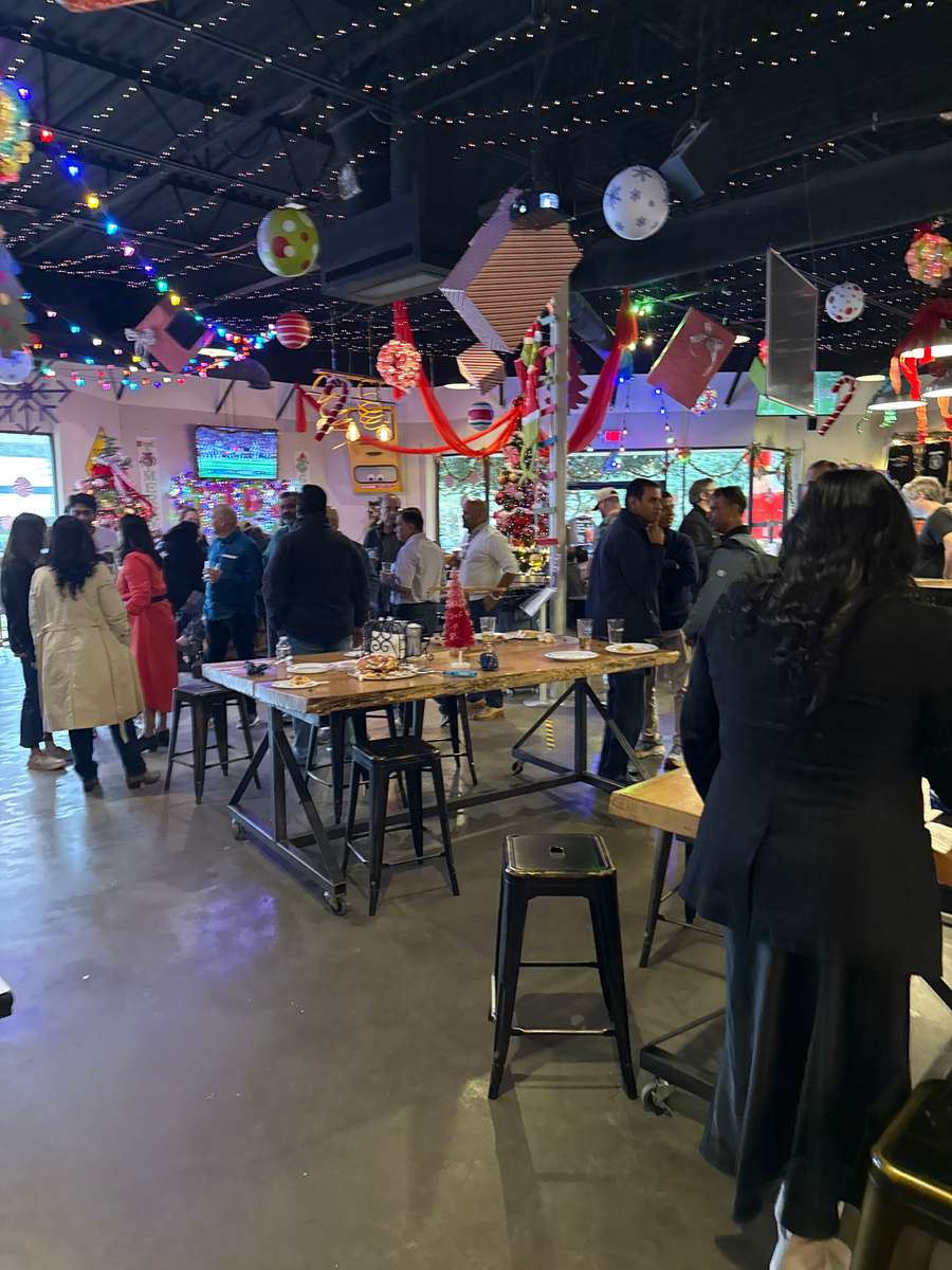Holiday party with guests gathered at long tables under string lights