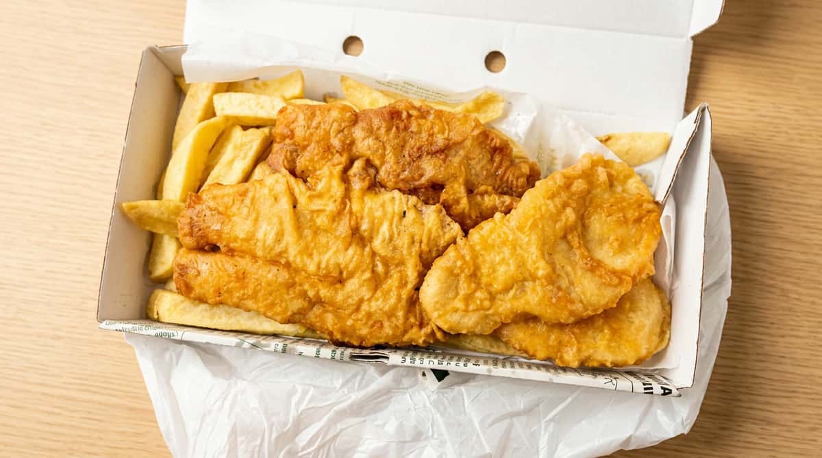 Golden battered fish served with thick-cut chips in a takeaway box at Blue Bay in Bridgeton.