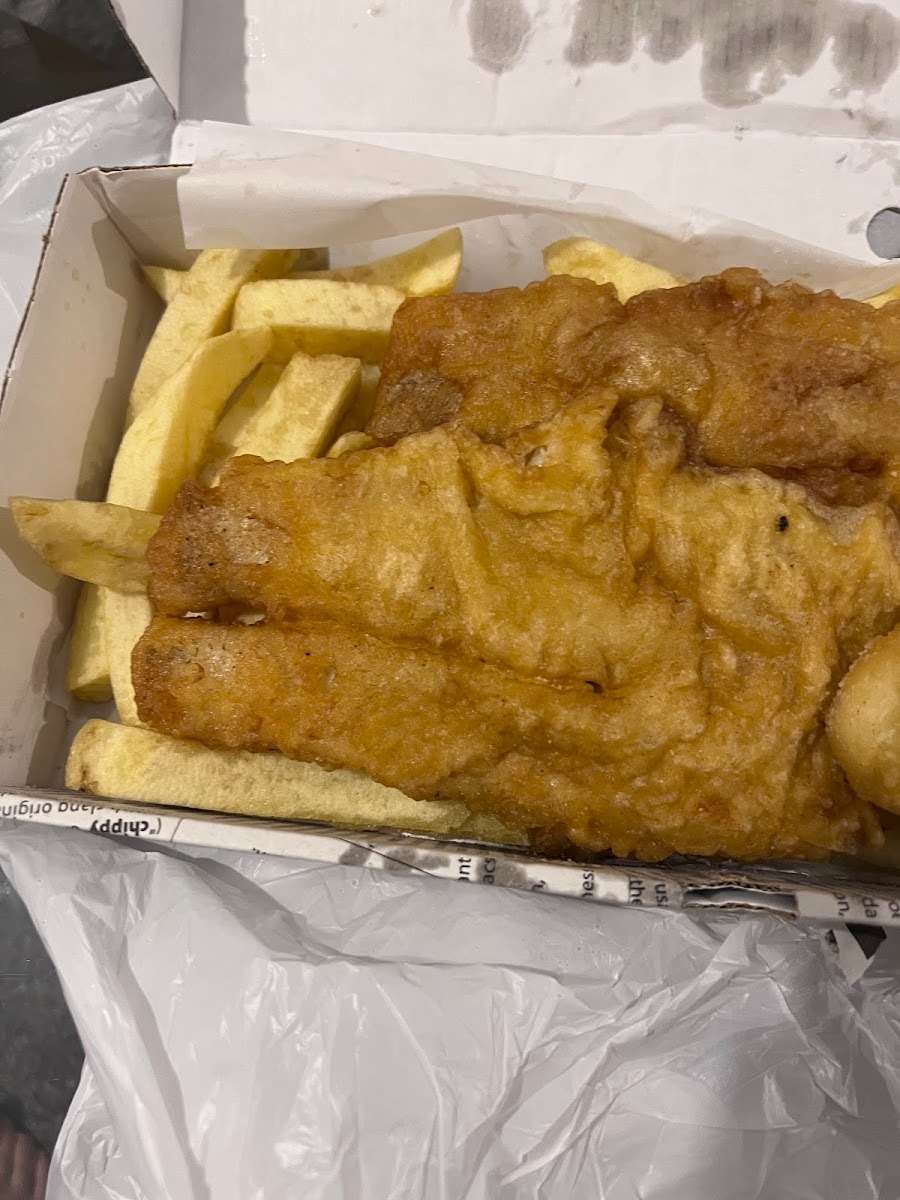 Large golden battered fish fillet served over chips at Blue Bay in Glasgow.