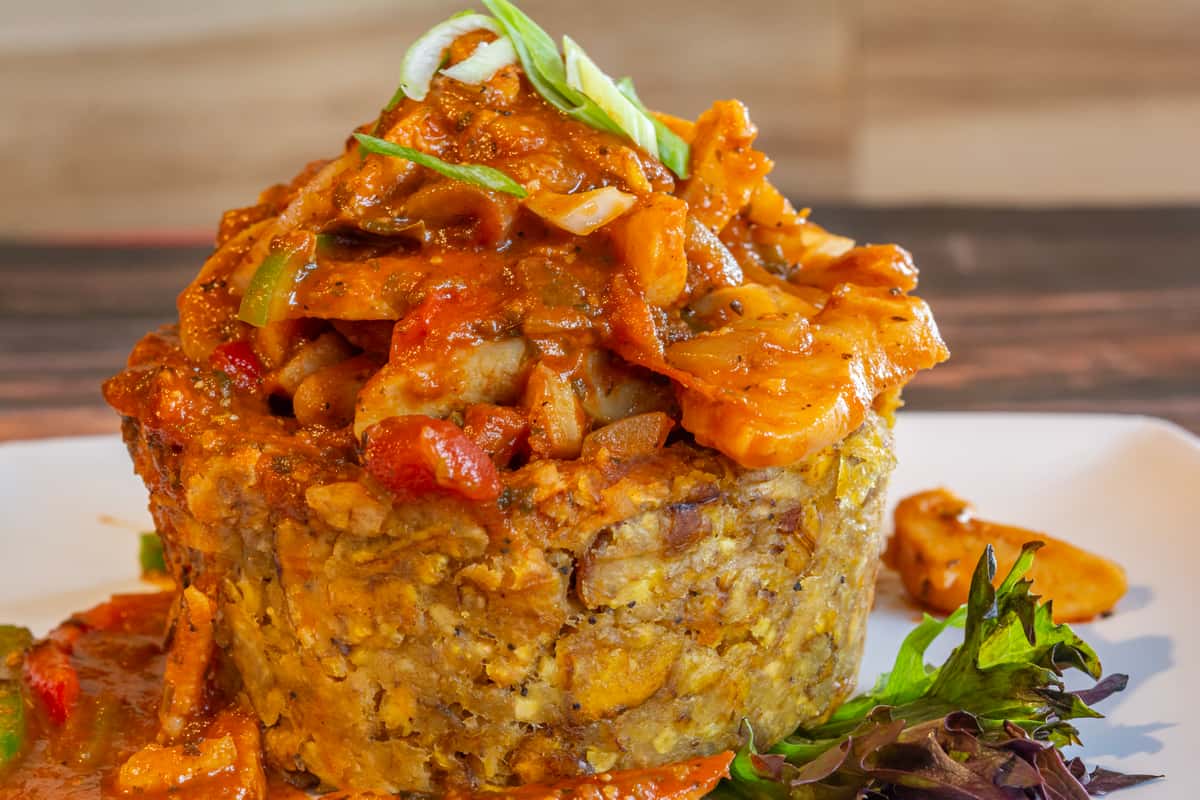 Hearty mofongo topped with savory red seafood creole sauce, loaded with shrimp, peppers, and onions—rich Caribbean flavor in every bite.
