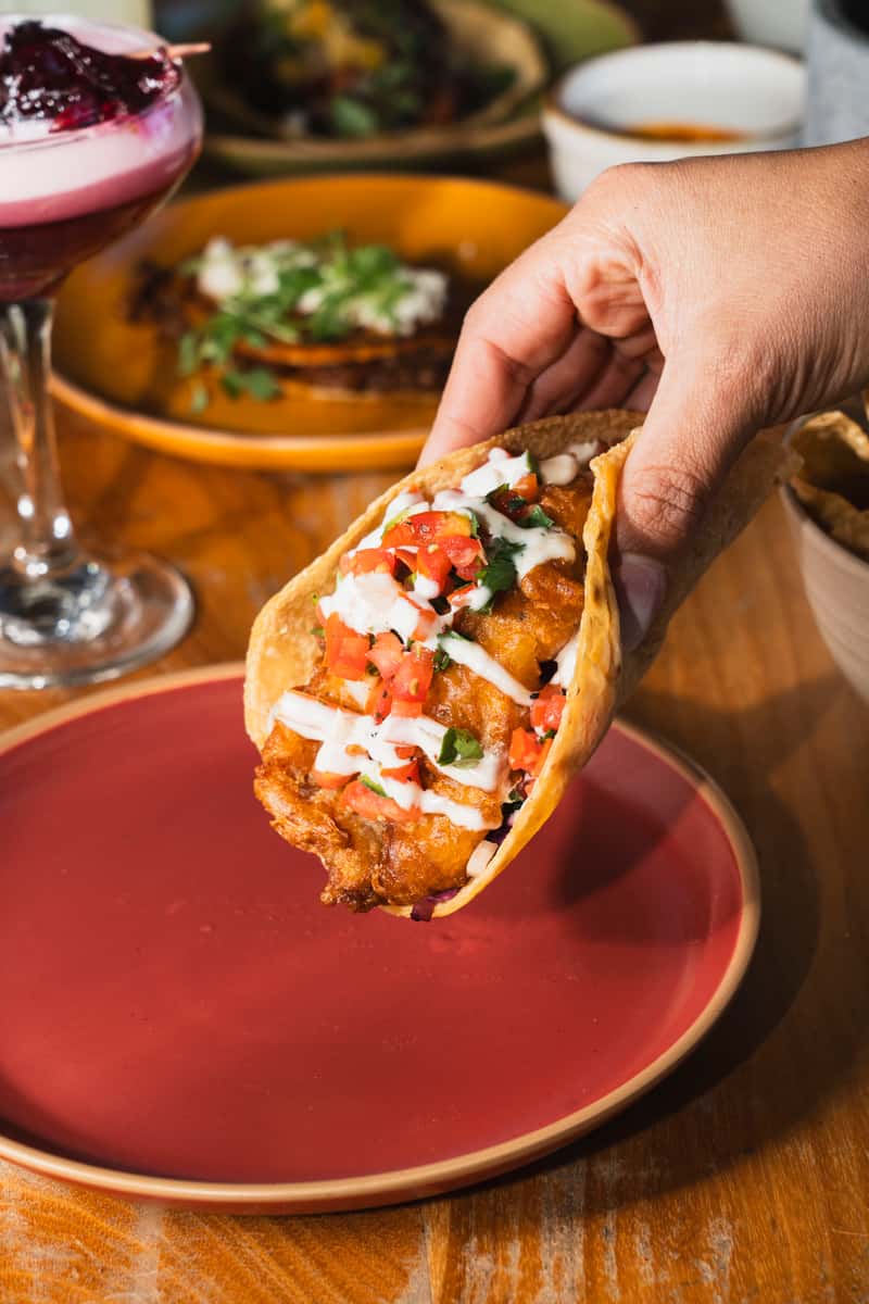 holding tacos with white sauce