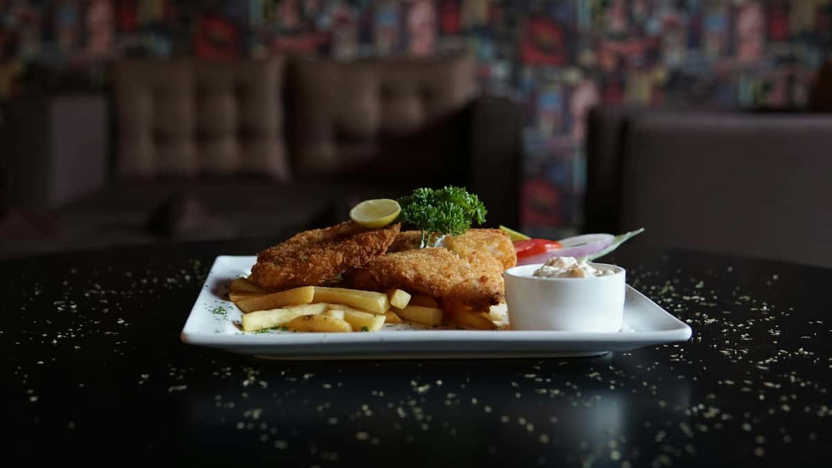 breaded fish and fries on a square white plate