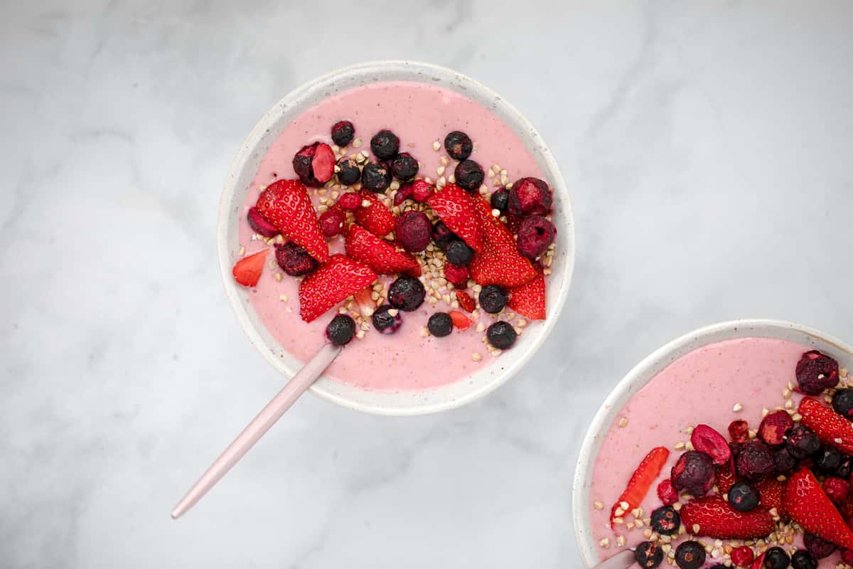 "Berry smoothie bowl topped with fresh strawberries, blueberries, raspberries, and granola, served in a white bowl for a healthy breakfast or dessert