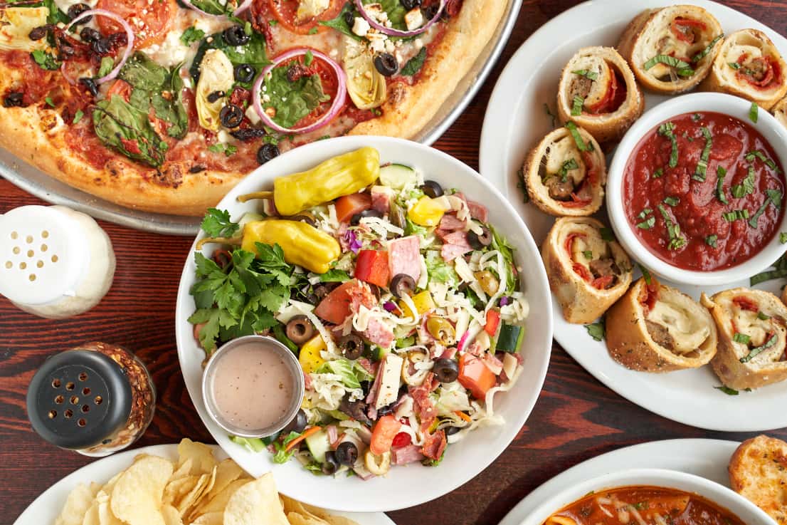 Greek salad with pizza rolls and a large pizza