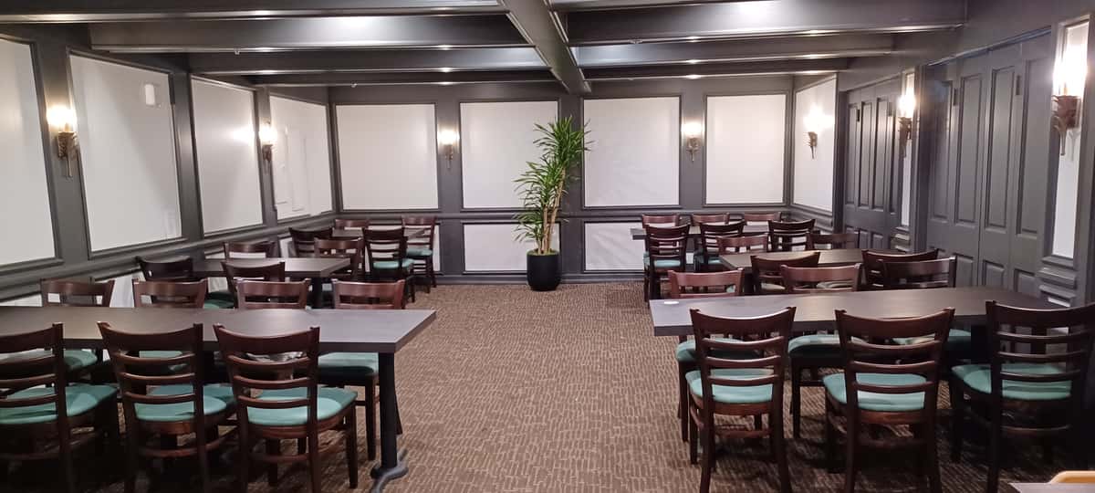 Spacious private dining room with dark wood accents, banquet-style seating, and elegant lighting for corporate events and group dining