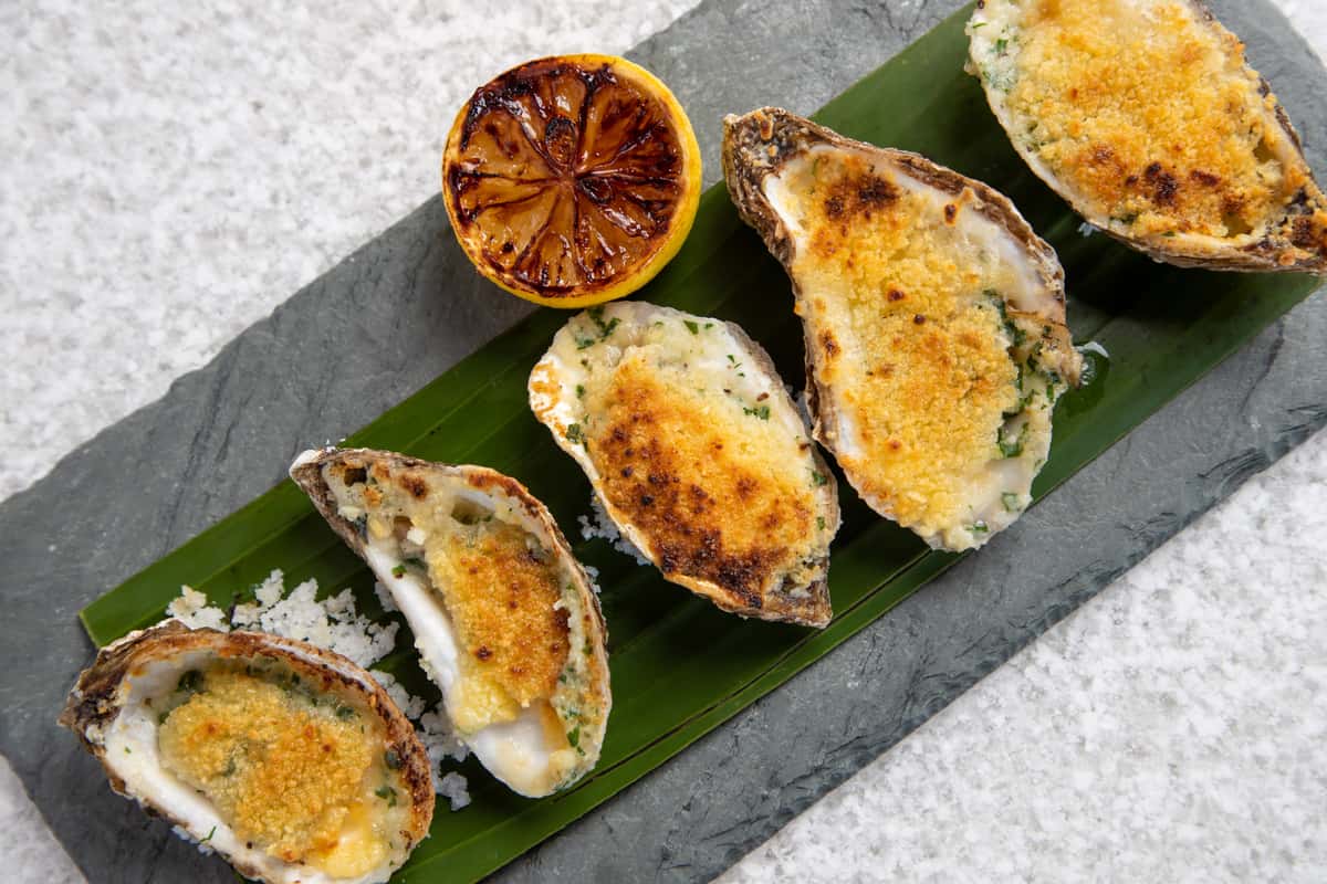 grilled oysters topped with parmesan cheese and served a lemon