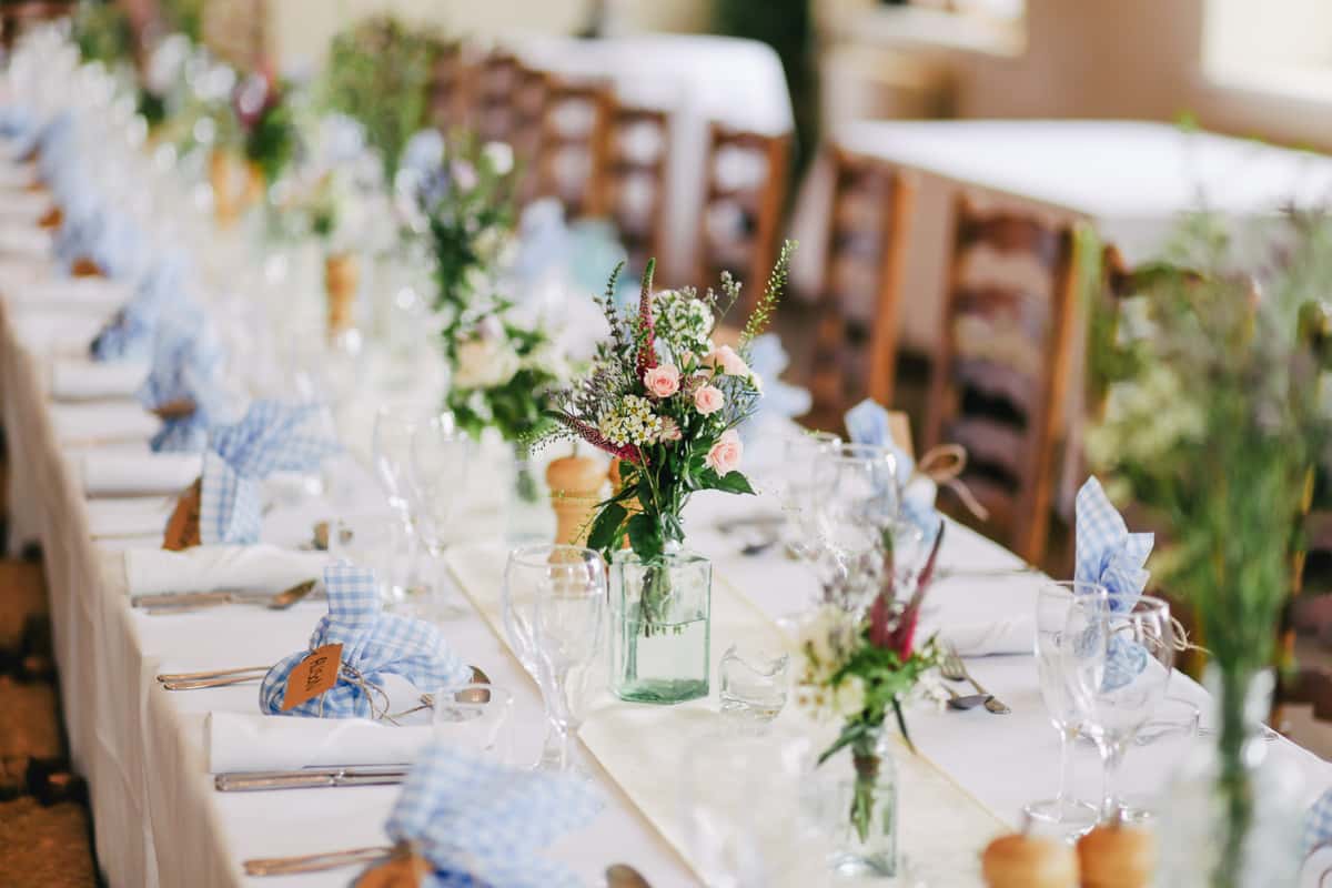 a country decorated table with flowers and table settings for a special event