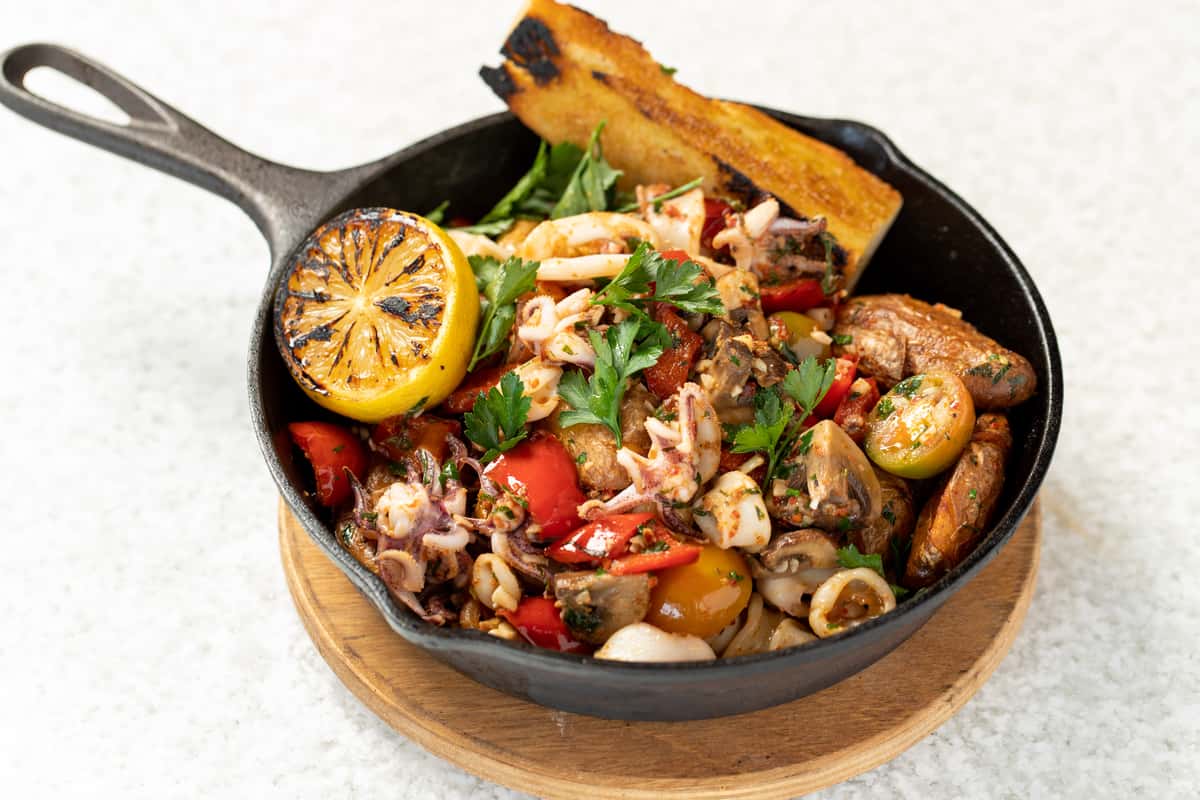sizzling calamari seafood dish in a cast iron skillet