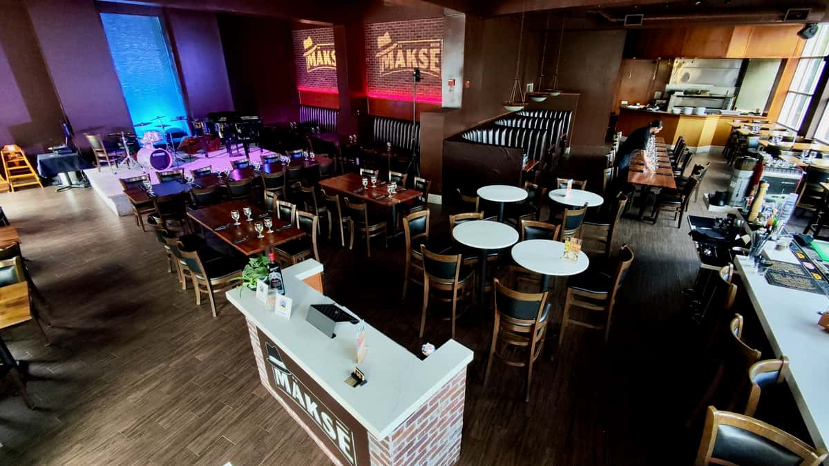 Spacious restaurant event space featuring dining tables, presentation area, and modern banquet layout