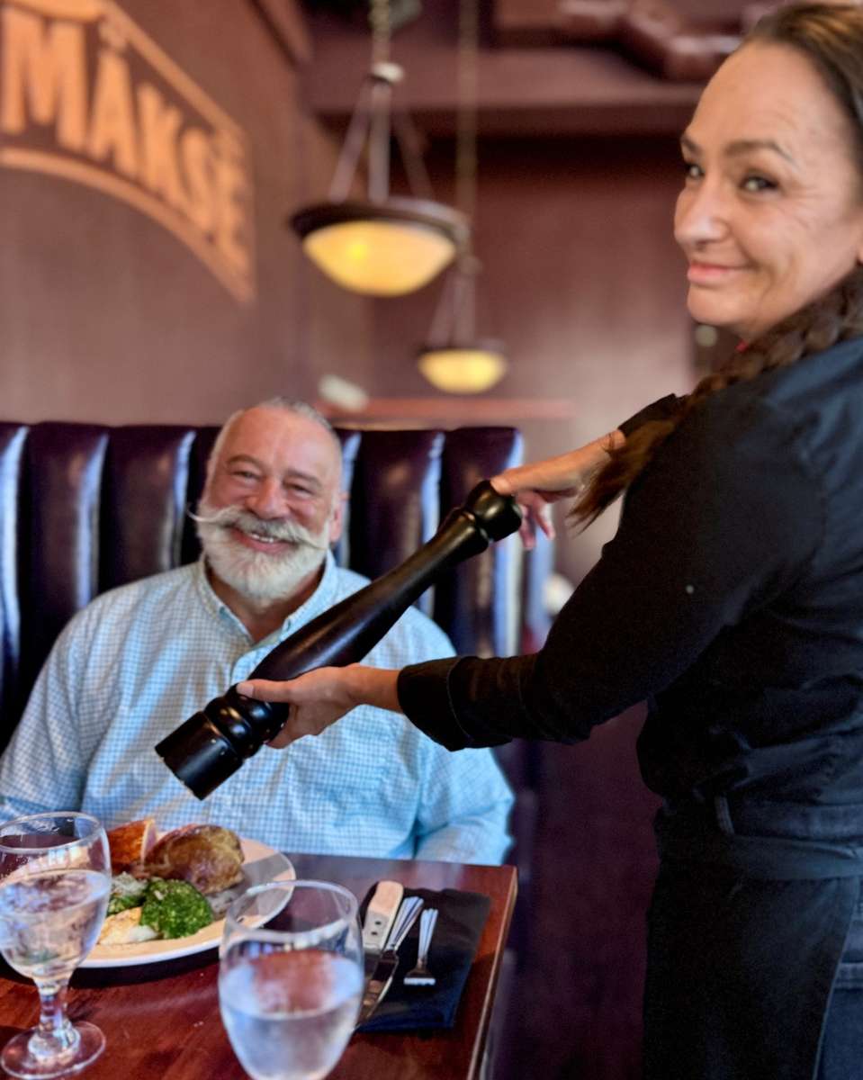 Restaurant server pouring wine for a guest during an elegant dining experience with personalized table service