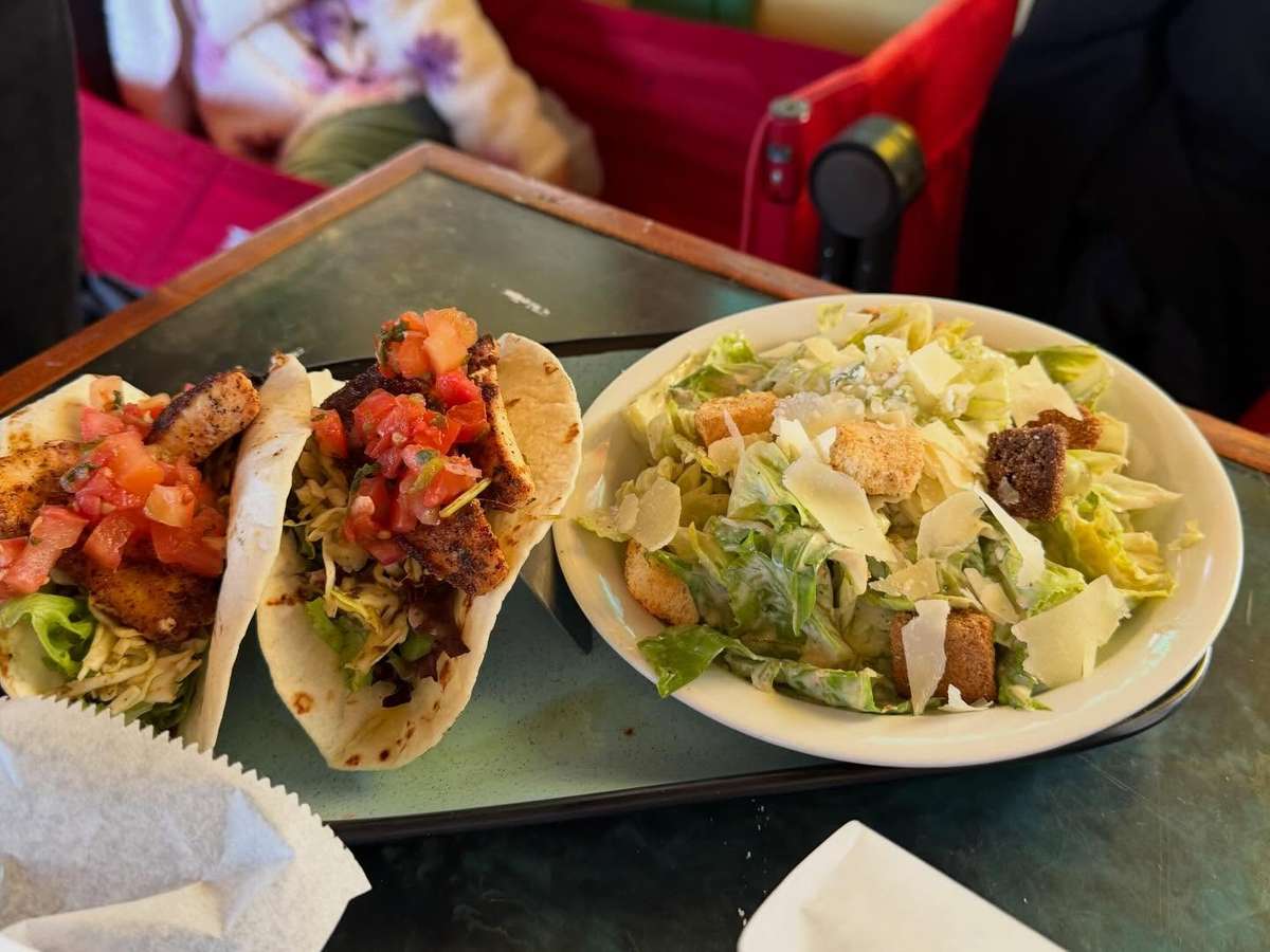 Blackened fish tacos topped with shredded lettuce and pico de gallo, served with a Caesar salad with croutons and shaved parmesan.