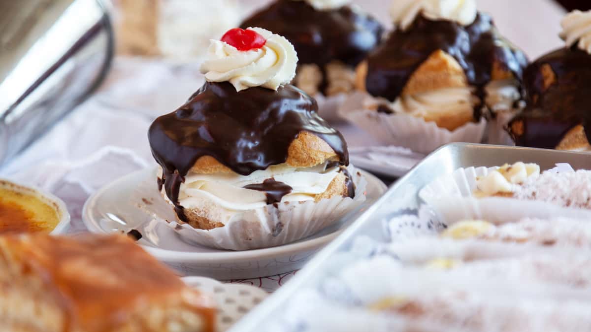 Cream puff pastries with chocolate glaze and a cherry