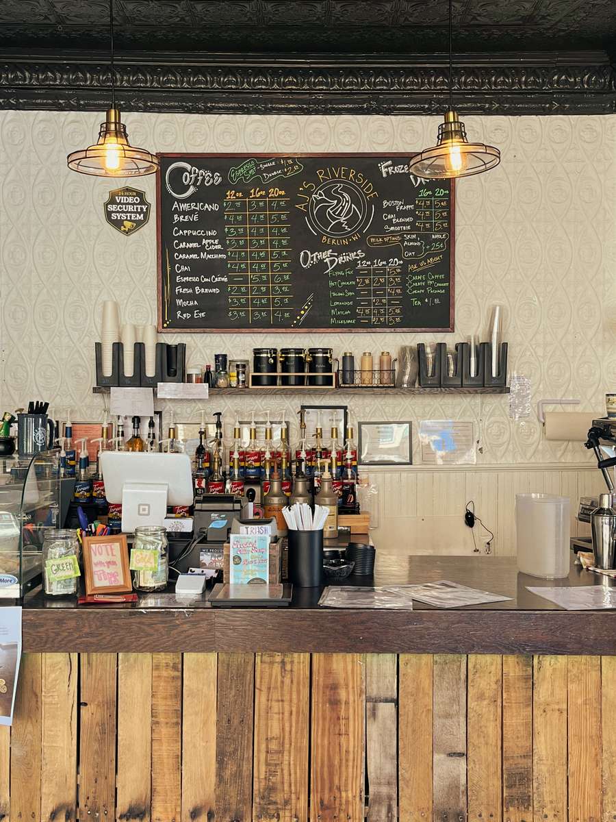 AJ's Riverside coffee shop counter with large chalkboard menu and rustic wooden front.