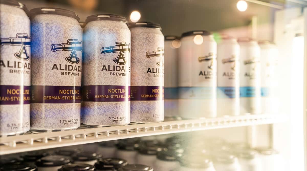 Alidade Brewing German-style black lager cans in a refrigerated display case.