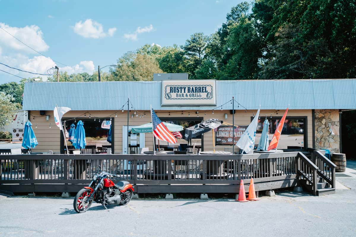 Exterior of The Rusty Barrel bar with numerous bikes in the parking lot