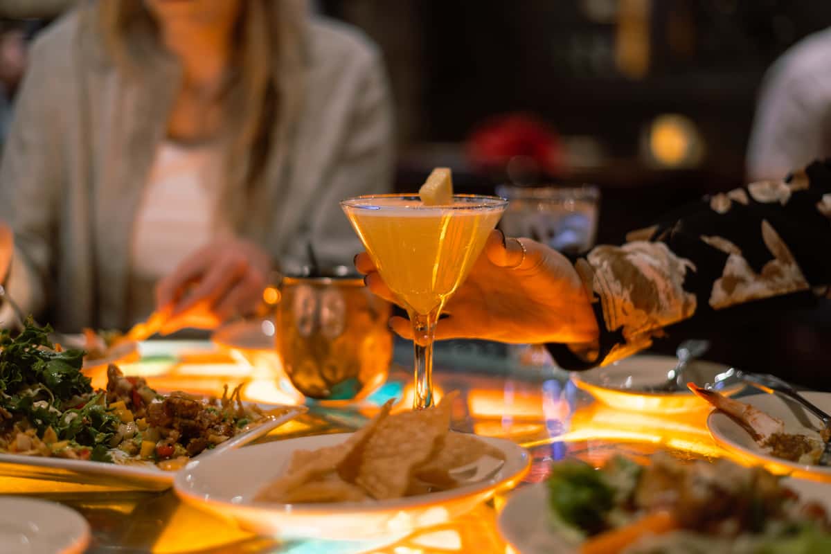 Espresso martini served alongside appetizers on a dining table.