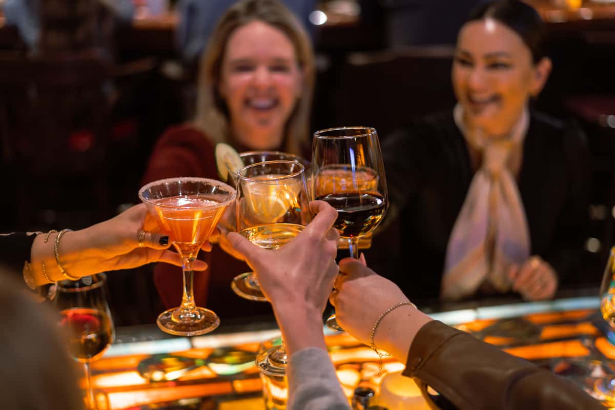 Friends raising cocktails in a celebratory toast during dinner.