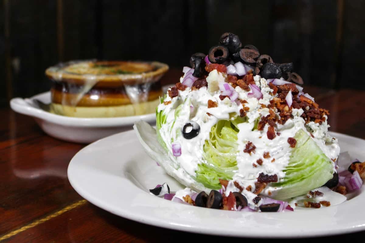 Classic iceberg wedge salad topped with bacon, blue cheese, and fresh herbs.