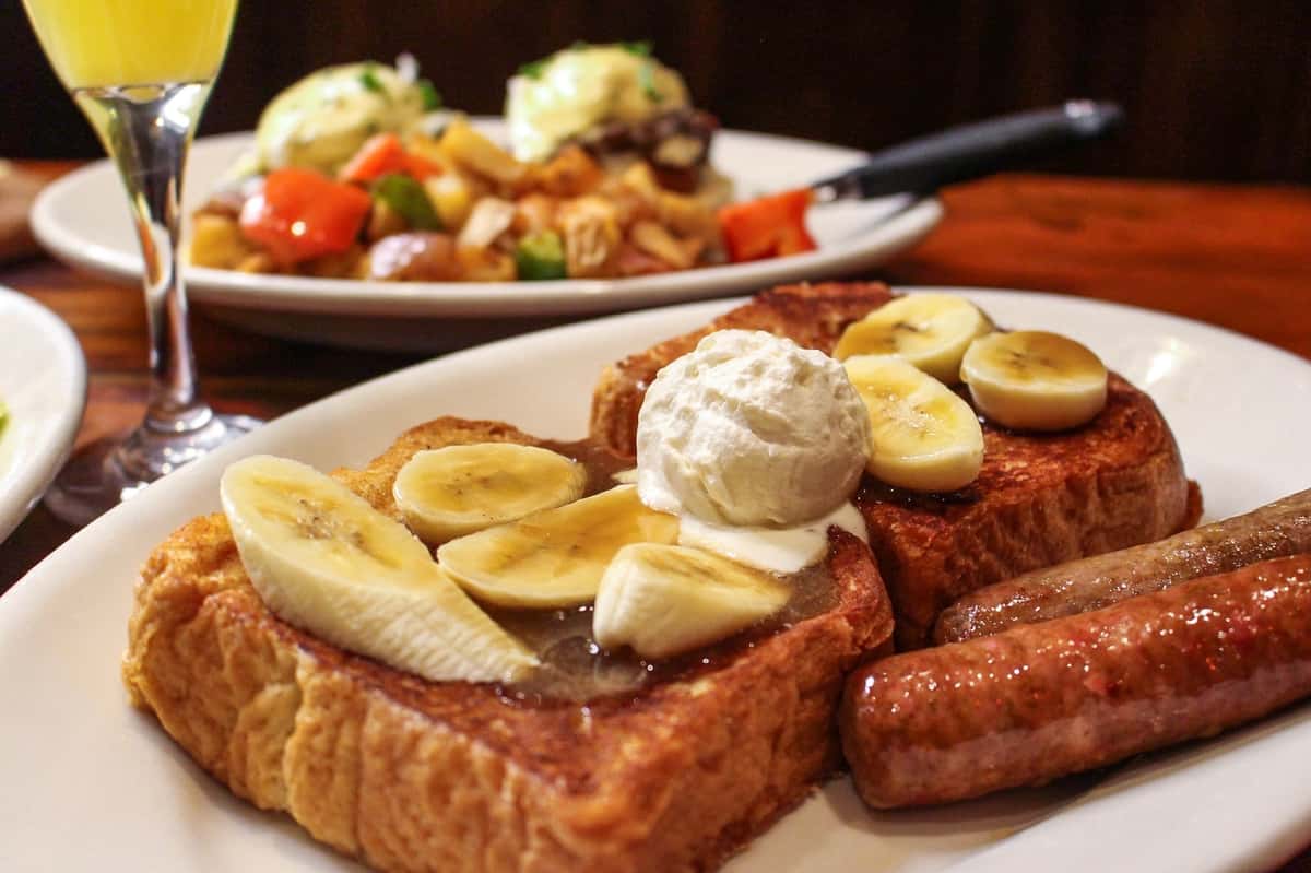 Bananas Foster French toast breakfast served with sausage and fresh fruit at Sperry's Restaurant.
