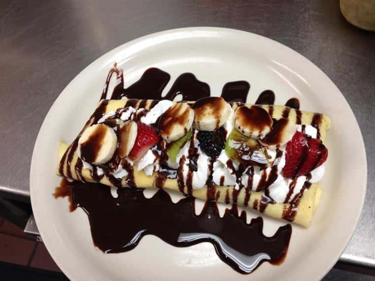 dessert topped with bananas, strawberries and chocolate drizzle