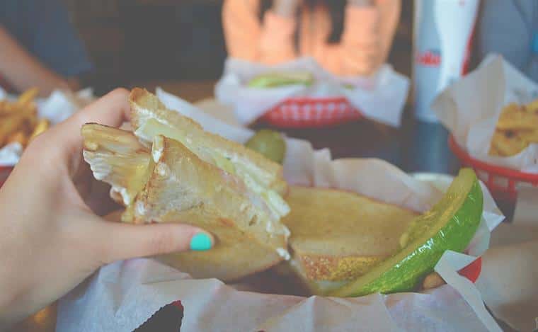 Club sandwich with pickles in basket.