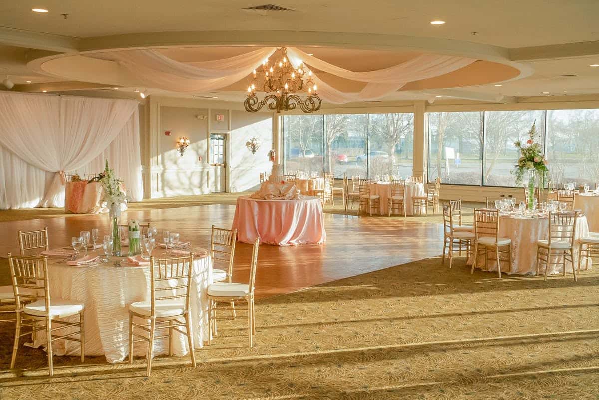 Grand ballroom event venue beautifully decorated in pink linens and white tables