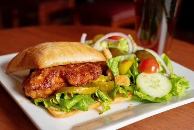 chicken sandwich with pickles and a side salad
