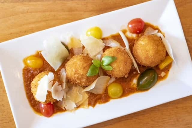 deep fried risotto balls topped with tomatoes 