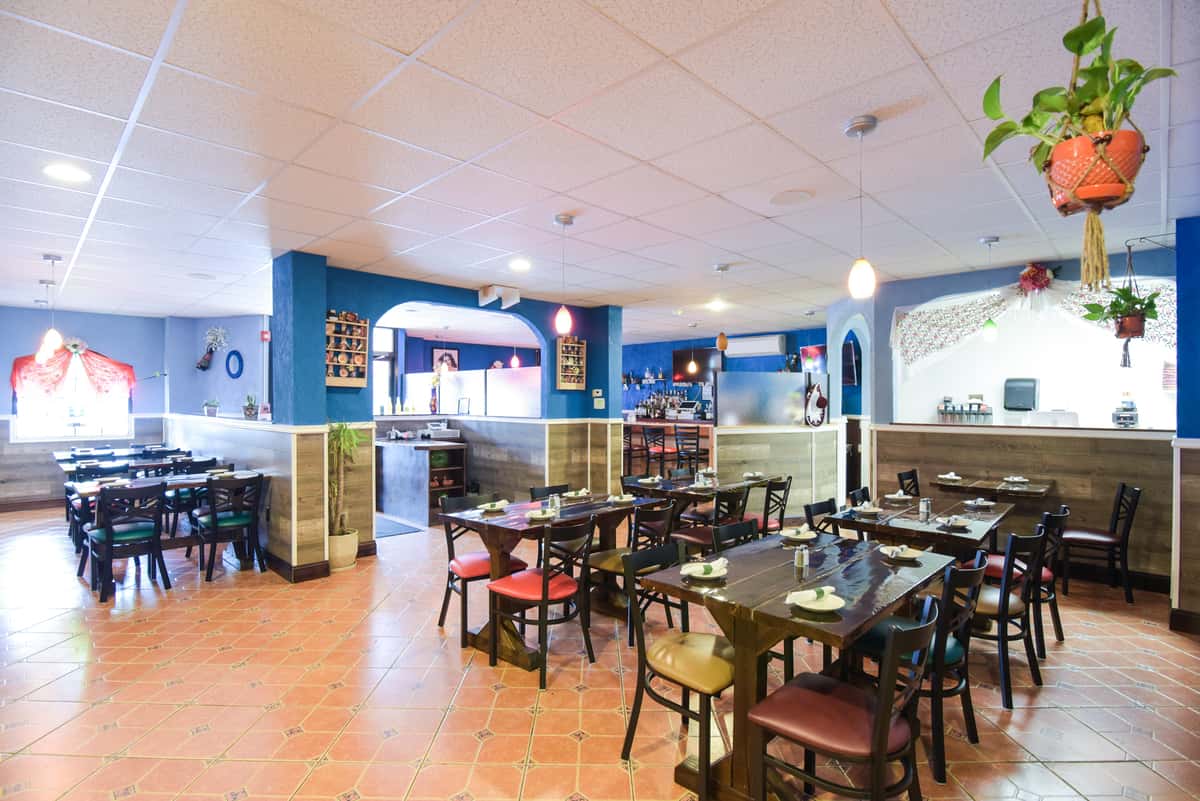 Gemini said An indoor restaurant dining area with blue walls, tiled floors, and dark wooden tables with red and tan chairs under a drop ceiling.