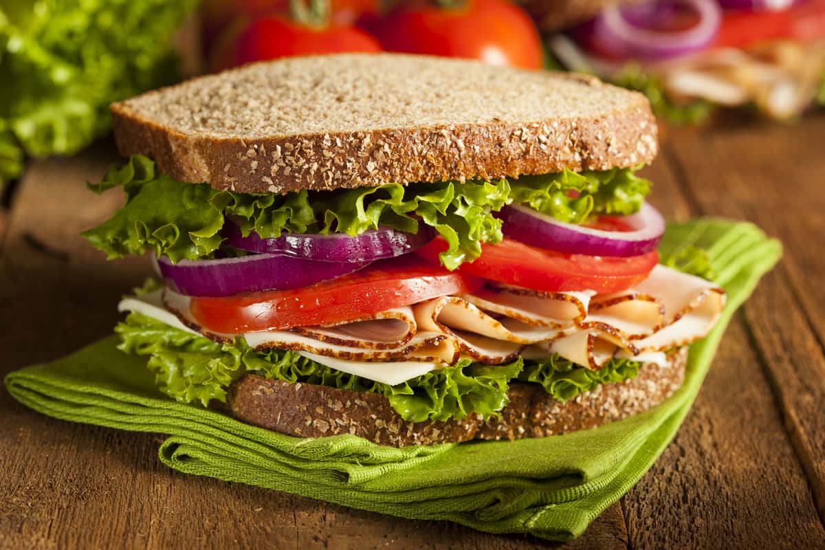 Stacked turkey club sandwich with onions, tomato and lettuce