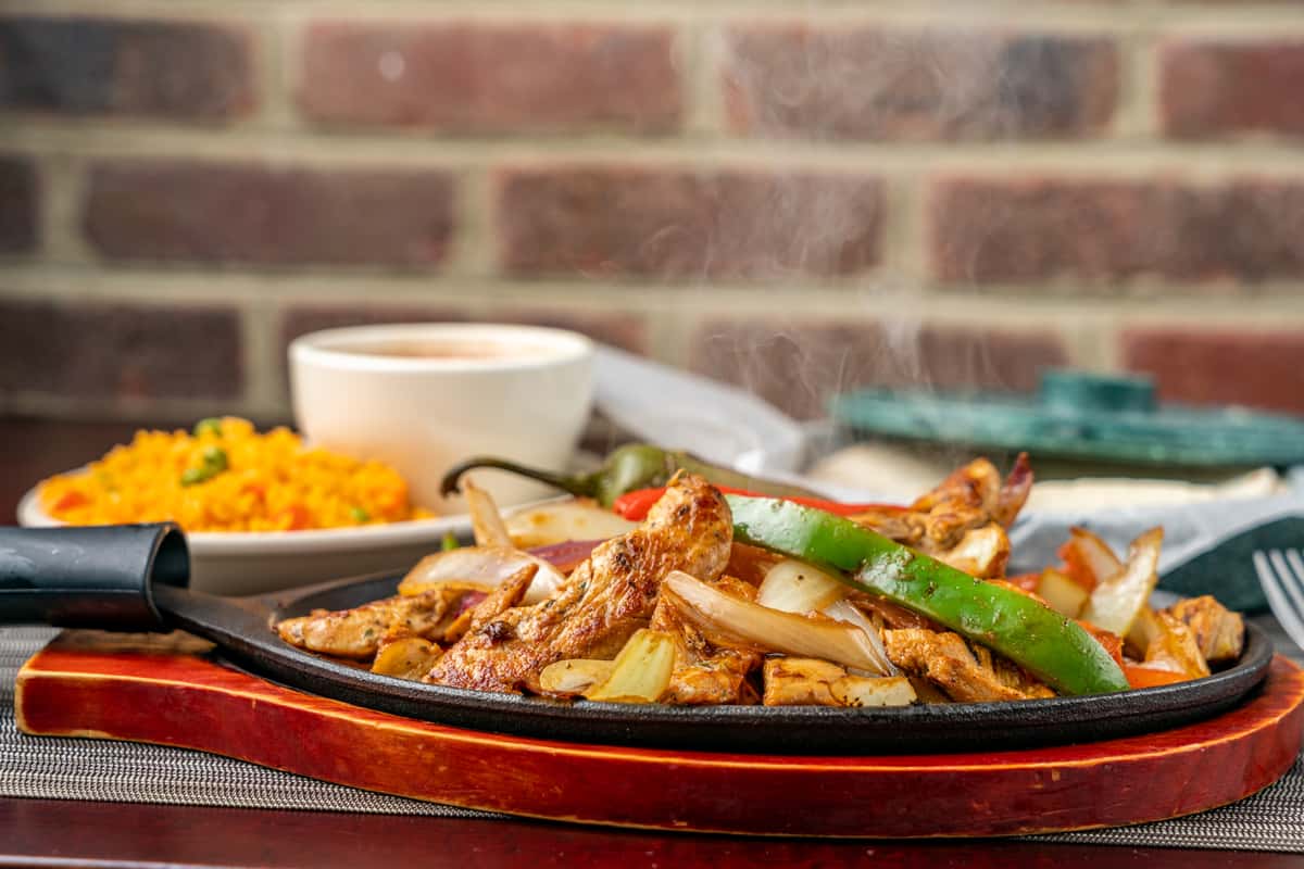 sizzling plate of meat and veggies