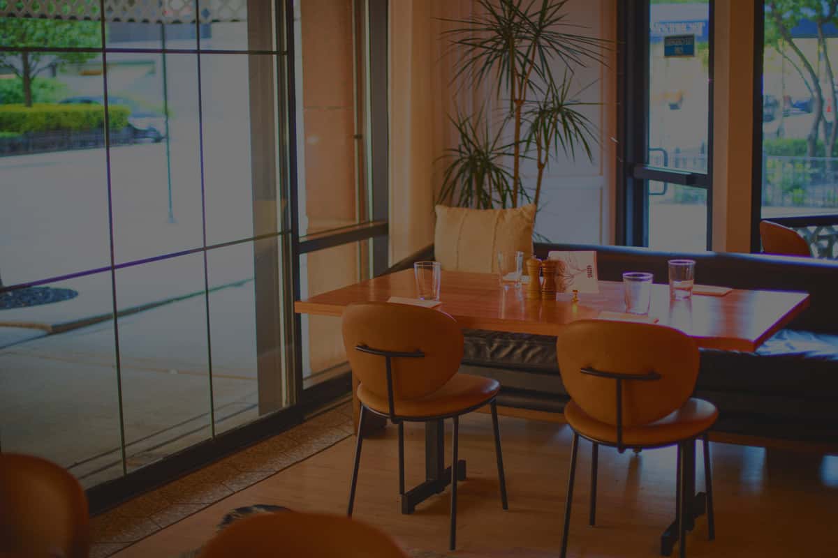Background displays the welcome and opening space of Chapel Street with tables and chairs and sun shining through the wall sized window.