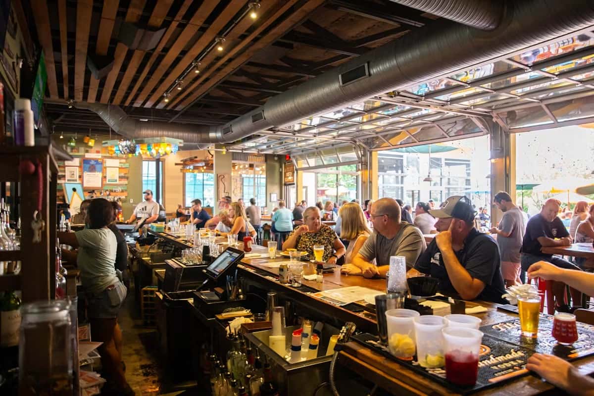 Busy interior of Crooked Hammock Brewery with patrons at the bar and tables, enjoying drinks in a lively, rustic atmosphere.