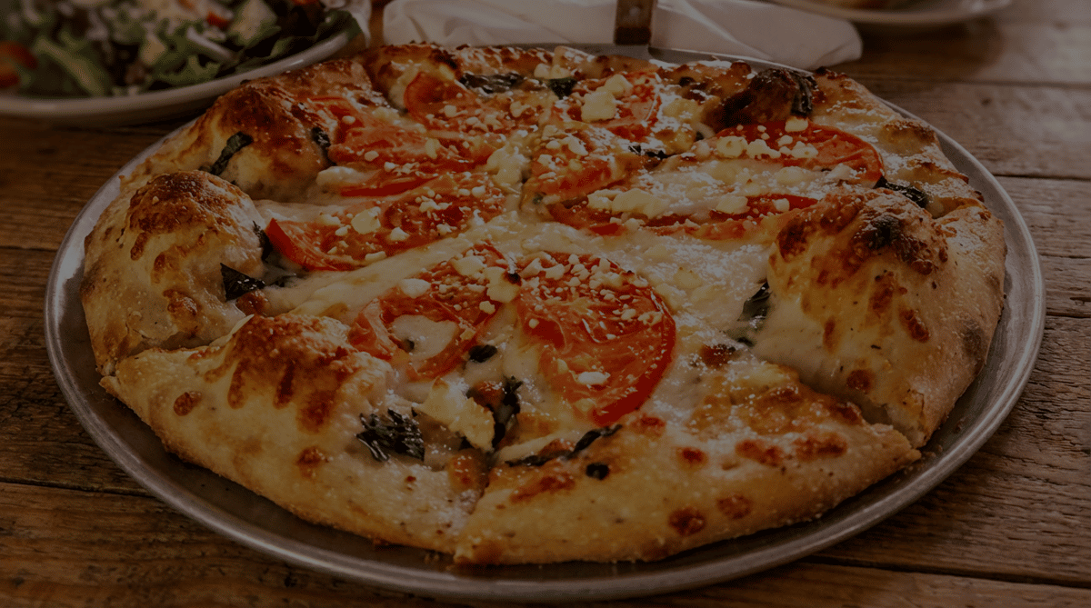 Tomato and feta pizza with melted mozzarella and green herbs.