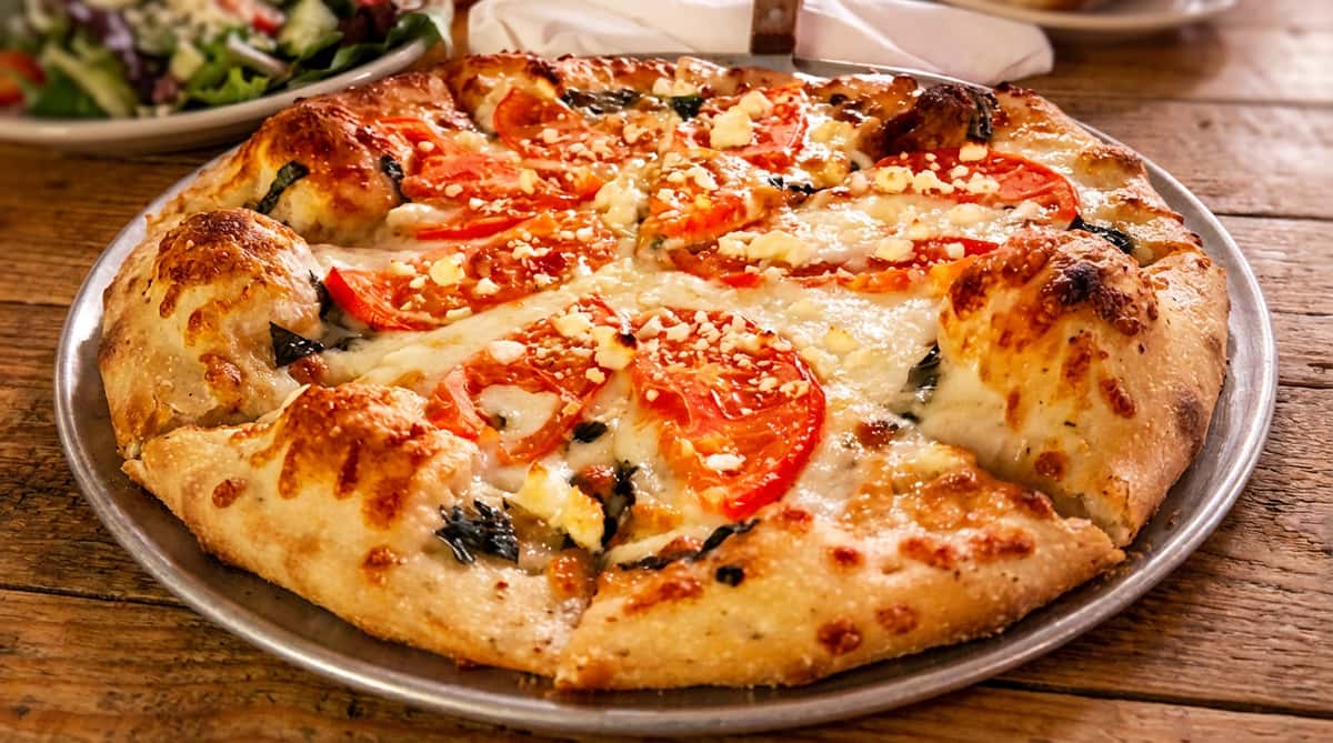 Tomato and feta pizza with melted mozzarella and green herbs.