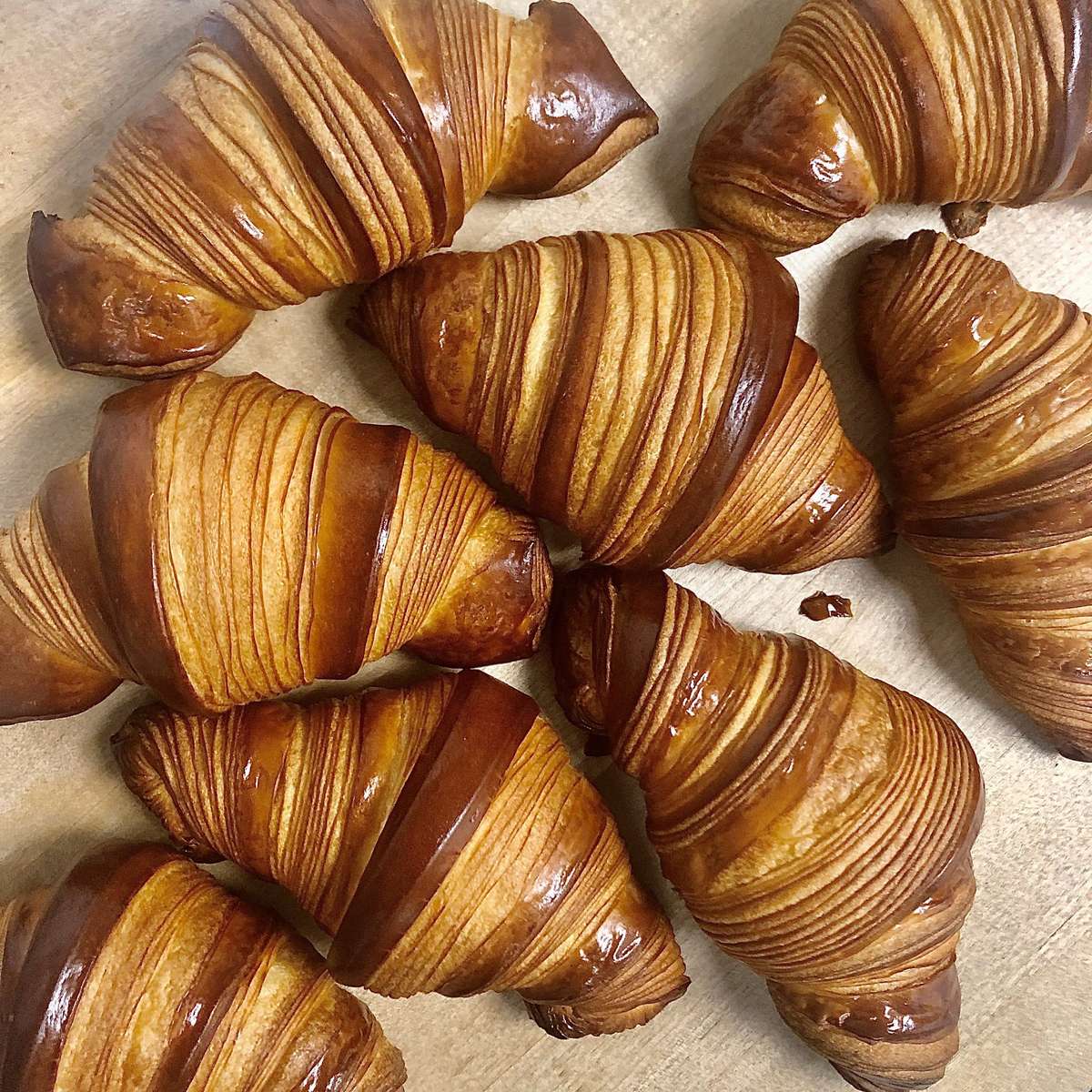 Flaky golden croissants with crisp layered pastry, freshly baked and arranged on parchment paper