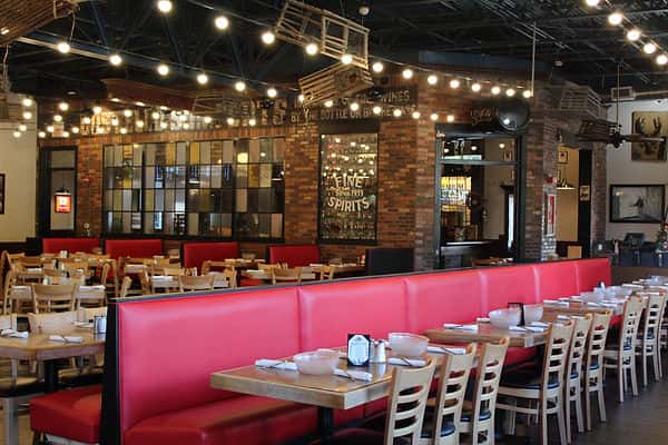 Dining room at Boston Lobster Feast with red booth seating, brick walls and string lights