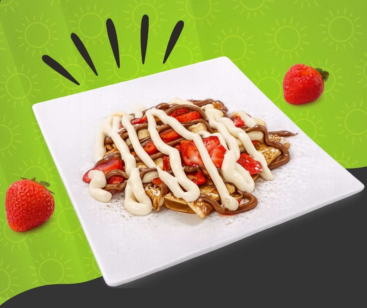 Sweet breakfast crepes drizzled with cream sauce and strawberry topping, served fresh at Cinnamon Restaurant Café.