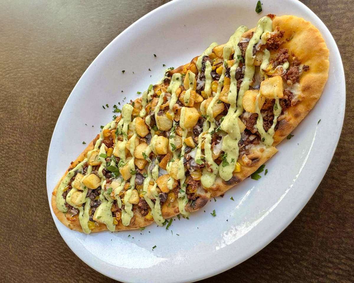 Flatbread topped with seasoned beef, roasted corn, diced potatoes, herbs, and drizzled with a creamy green sauce.