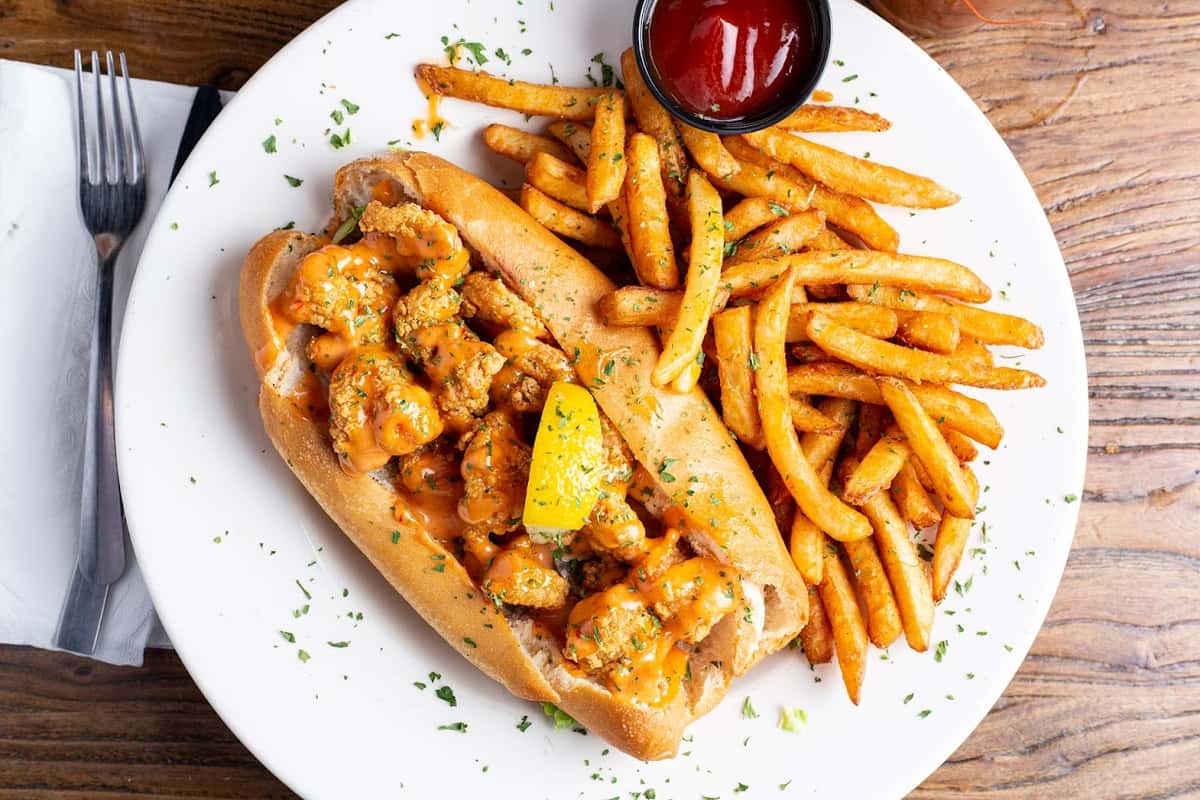 fried shrimp sandwich with sauce and fries with ketchup