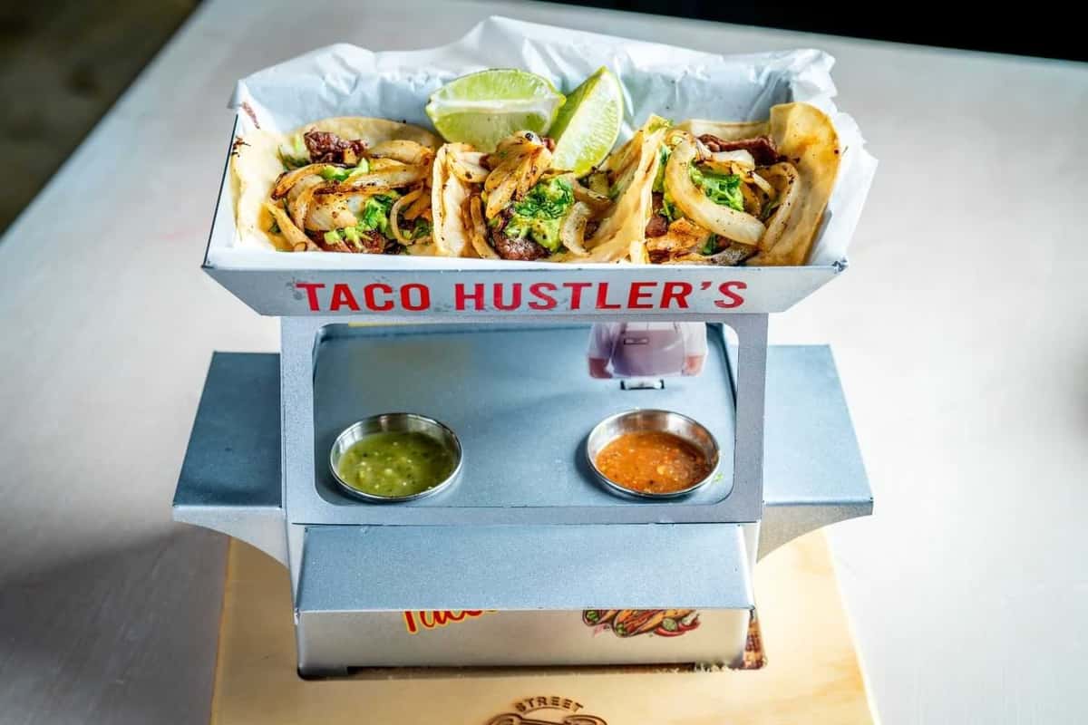 Mini taco stand presentation featuring street tacos with grilled meat, onions, cilantro, and lime wedges, served with house-made salsas for a vibrant Mexican dining experience.